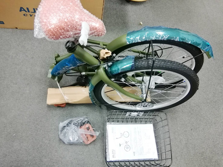 自転車はこのように分かれていて、少し自分で組み立てる必要があります。同梱品は折り畳み自転車本体の他に、サドルとハンドル、前かごとペダル、フロントライトやワイヤー錠、その他、留め具や取扱説明書が入っています。